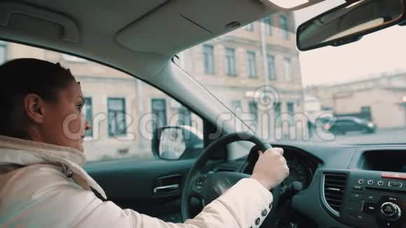 担心穿着白色夹克的年轻女人开着车在城市大街上视频的预览图