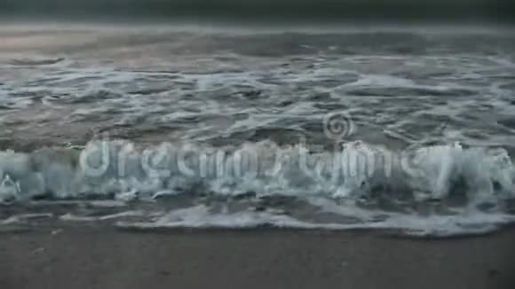 海浪冲刷着岸边的沙傍晚昏暗的灯光黎明慢动作视频的预览图
