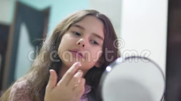 小女孩在室内女学生涂面霜面部护理女孩青少年涂抹面部室内霜视频的预览图