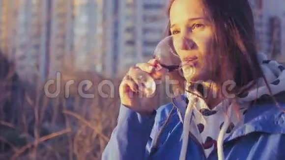 一个手里拿着一杯酒的女孩在大自然和日落时休息4K3840x2160视频的预览图