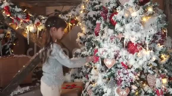 圣诞节或新年孩子们迷人地看着新年树有毛的小女孩把圣诞玩具挂在耳朵上视频的预览图