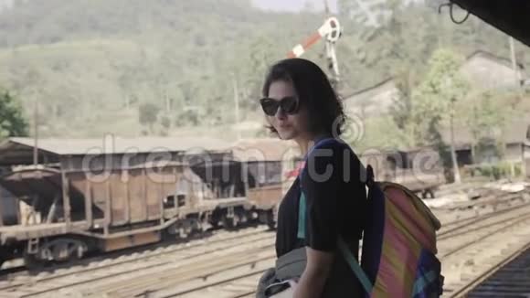 微笑的旅行女孩看着你在亚洲贫困火车站视频的预览图