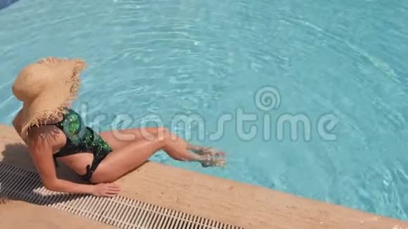 一个戴着草帽的女人在蓝色的游泳池里放松俯视图慢动作视频的预览图