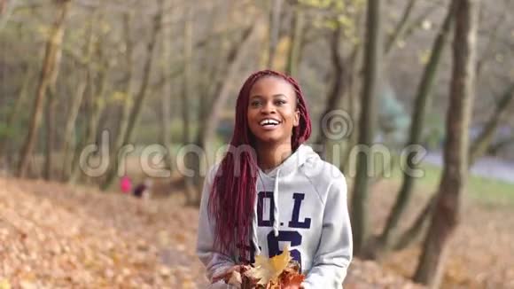 这位美丽的非洲裔美国妇女正在秋天的公园里玩得很开心那个女孩正在扔黄叶子视频的预览图