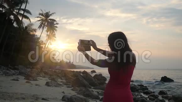 布鲁内特女士在海滩上的智能手机上拍摄日落的照片慢动作1920x1080视频的预览图