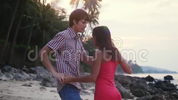 日落时分漂亮的年轻夫妇在热带海滩上慢舞慢动作1920x1080视频的预览图