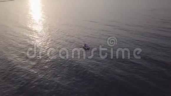 日落时在碧海中航行的观光船的鸟瞰图视频的预览图