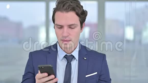 开朗的年轻商人用智能手机说话的画像视频的预览图