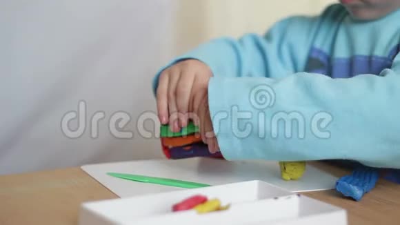 儿童的手臂在桌上用橡皮泥雕刻图形视频的预览图