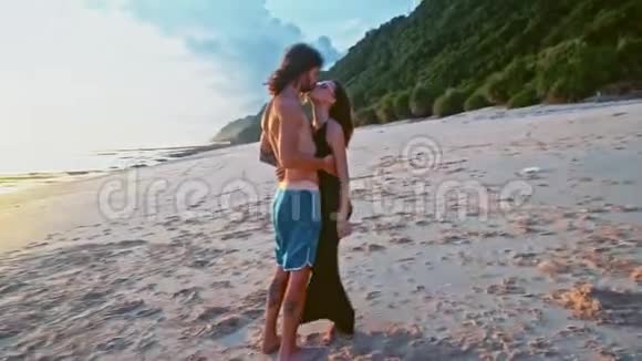 迷人的在爱情中美丽的年轻旅行夫妇享受日落在海滩上亲吻和拥抱慢动作海洋视频的预览图