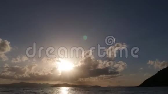 一片美丽的蓝天太阳从云层和岛屿后面沉入大海视频的预览图