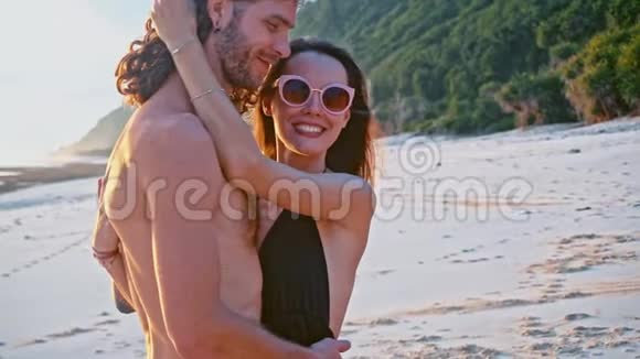 迷人的在爱情中美丽的年轻旅行夫妇享受日落在海滩上亲吻和拥抱慢动作海洋视频的预览图