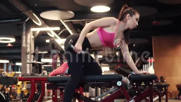 运动女孩在健身房用哑铃做运动穿运动服的女孩做三头肌练习侧视视频的预览图