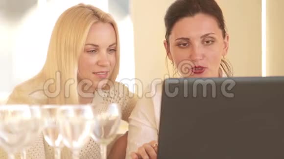 两个迷人的年轻女孩坐在笔记本电脑前热情地讨论着什么视频的预览图