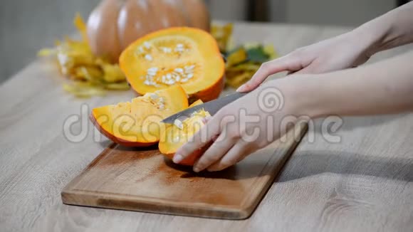女人在木制厨房桌子上清洗南瓜男性准备切橙色南瓜片视频的预览图
