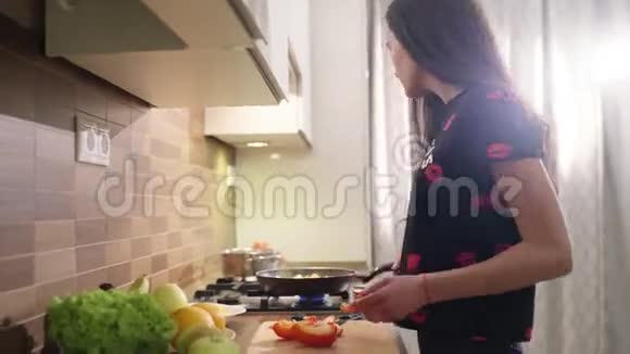 穿着睡衣的漂亮快乐女孩正在家做早餐蔬菜她正在清洗一些红辣椒视频的预览图
