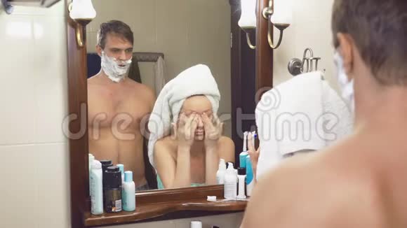 美丽的夫妻男人和女人一起在镜子前的浴室里洗4K慢动作干扰视频的预览图