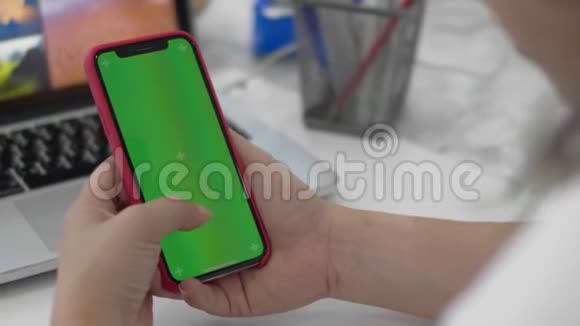 女人用智能手机看手机上的绿色屏幕视频的预览图