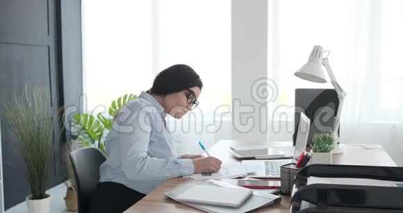 女商人在办公室做文书工作时使用笔记本电脑视频的预览图