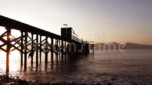 日出时海滩码头剪影视频的预览图