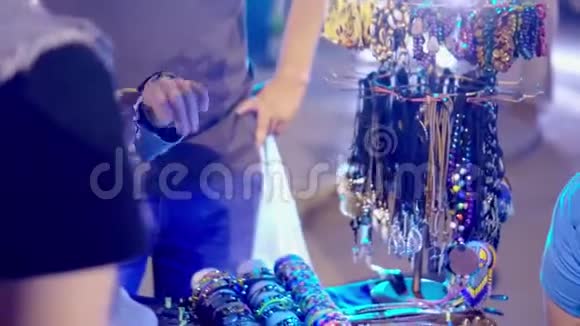 人们在夜城观看带有珠宝的集市柜台人们在蓝色的灯光下观看手镯视频的预览图