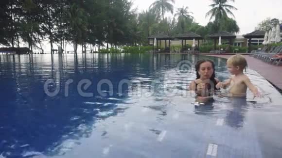 有女儿的年轻女子闻着游泳池里的梅花视频的预览图