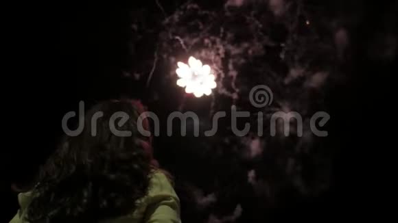 夜晚的女孩看着天空中的烟火美丽的烟花在夜间假日新年生日女孩视频的预览图
