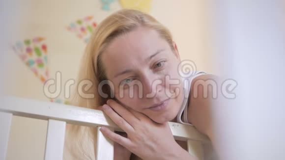 一个女人站在婴儿床前欣赏她的小睡宝宝视频的预览图