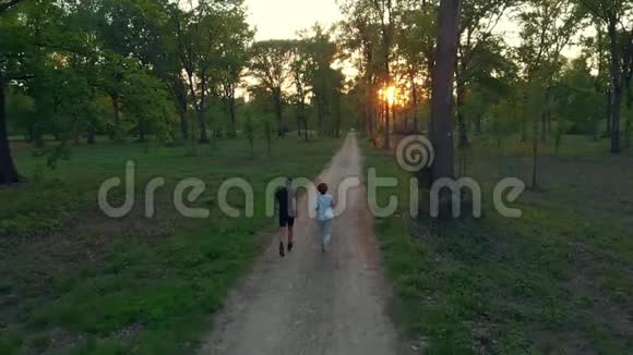 空中无人机跟踪情侣在乡村公路上穿越森林公园户外活动健身的概念视频的预览图