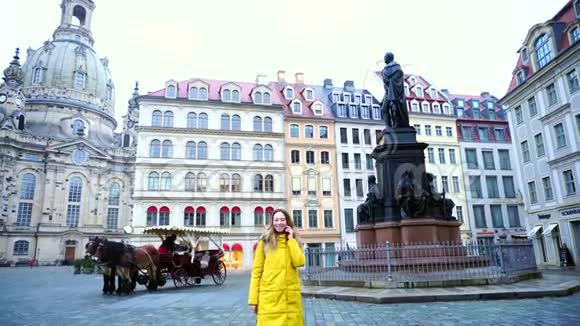 迷人的女孩在欧洲城市德累斯顿的电话聊天在美丽的房子和纪念碑的背景下散步视频的预览图