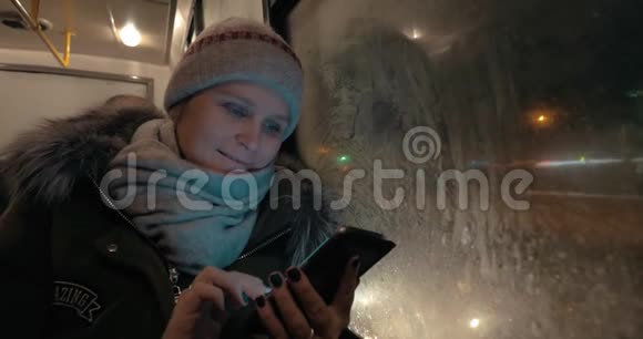 冬天晚上乘公共汽车时用手机的女人视频的预览图