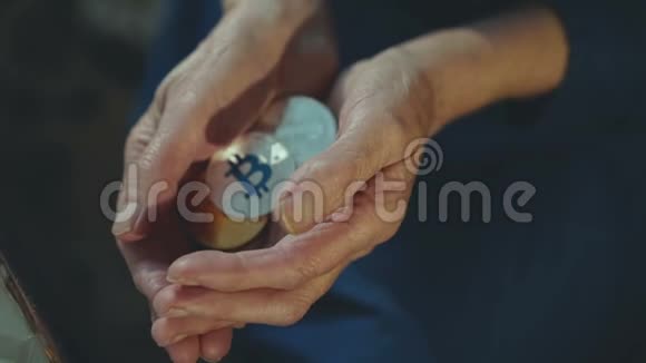 皱巴巴的老女人手里握着许多金色和银色的比特币视频的预览图