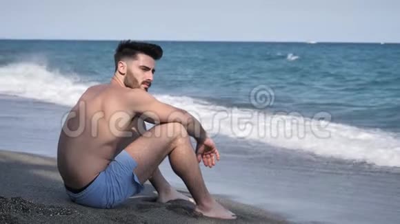 坐在沙滩上玩沙子的年轻人视频的预览图