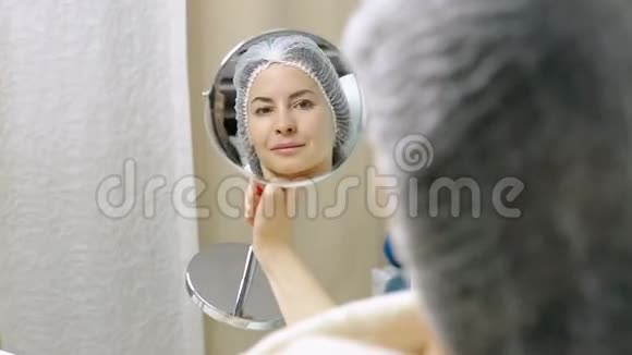 美丽的女人在美容院做过整容手术后照镜子视频的预览图