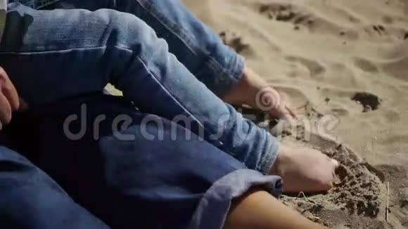 孩子们穿着牛仔裤在沙滩上的脚视频的预览图