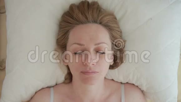 一个躺在床上的女人睁开眼睛微笑特写镜头从上面看视频的预览图