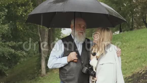 老人和年轻女子在公园的伞下散步视频的预览图