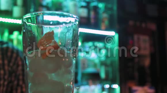 关闭酒吧玻璃和调酒师在酒吧柜台上的绿色灯光背景视频的预览图