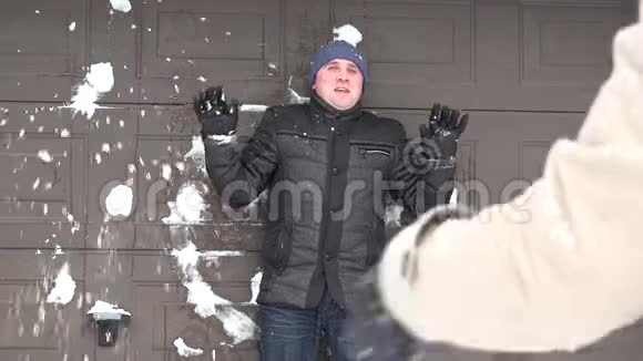 一个人站在墙边有人朝他扔雪球下雪视频的预览图