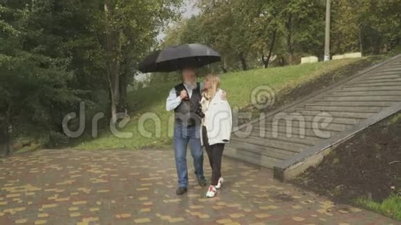 老人在公园下雨时和年轻女子散步方便结婚视频的预览图