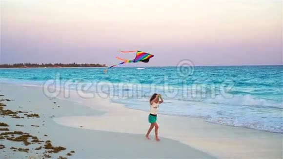 在热带海滩放风筝的小女孩孩子在海边玩带沙滩玩具的儿童慢动作视频的预览图