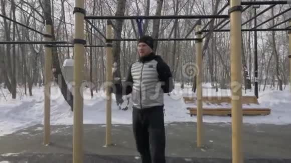 运动员在冬季运动场上与运动拓展者一起做深蹲运动视频的预览图