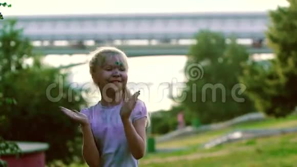 城市公园里金发小女孩拍手跳跃和转身的肖像视频的预览图