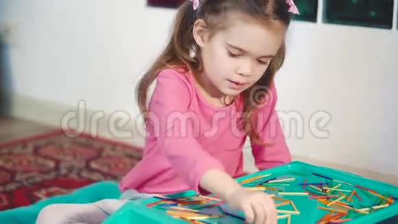 女孩在地板上玩五颜六色的木棍视频的预览图