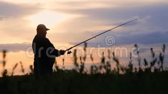 剪影渔夫在背景黄昏日落时在河中投掷鱼竿钓鱼时傍晚美丽的日落视频的预览图