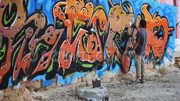 涂鸦艺术家在街墙上画画帅气的男人用喷雾瓶喷着五颜六色的油漆城市视频的预览图