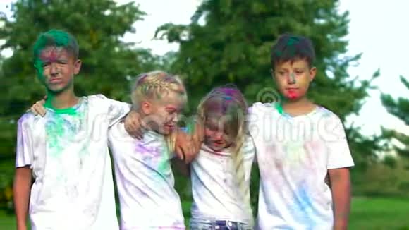 四个友好的孩子的肖像两个男孩和两个金发女孩站在镜头前互相拥抱视频的预览图