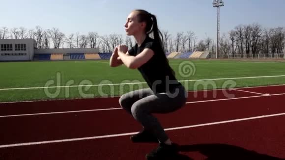 年轻有魅力的健身运动女性在户外大体育场锻炼身体做深蹲热身运动视频的预览图