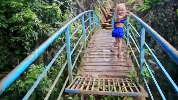 小金发女孩在公园的峡谷微笑上沿着大桥漫步视频的预览图