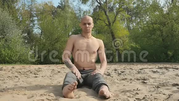年轻人坐在沙子上的莲花位置视频的预览图